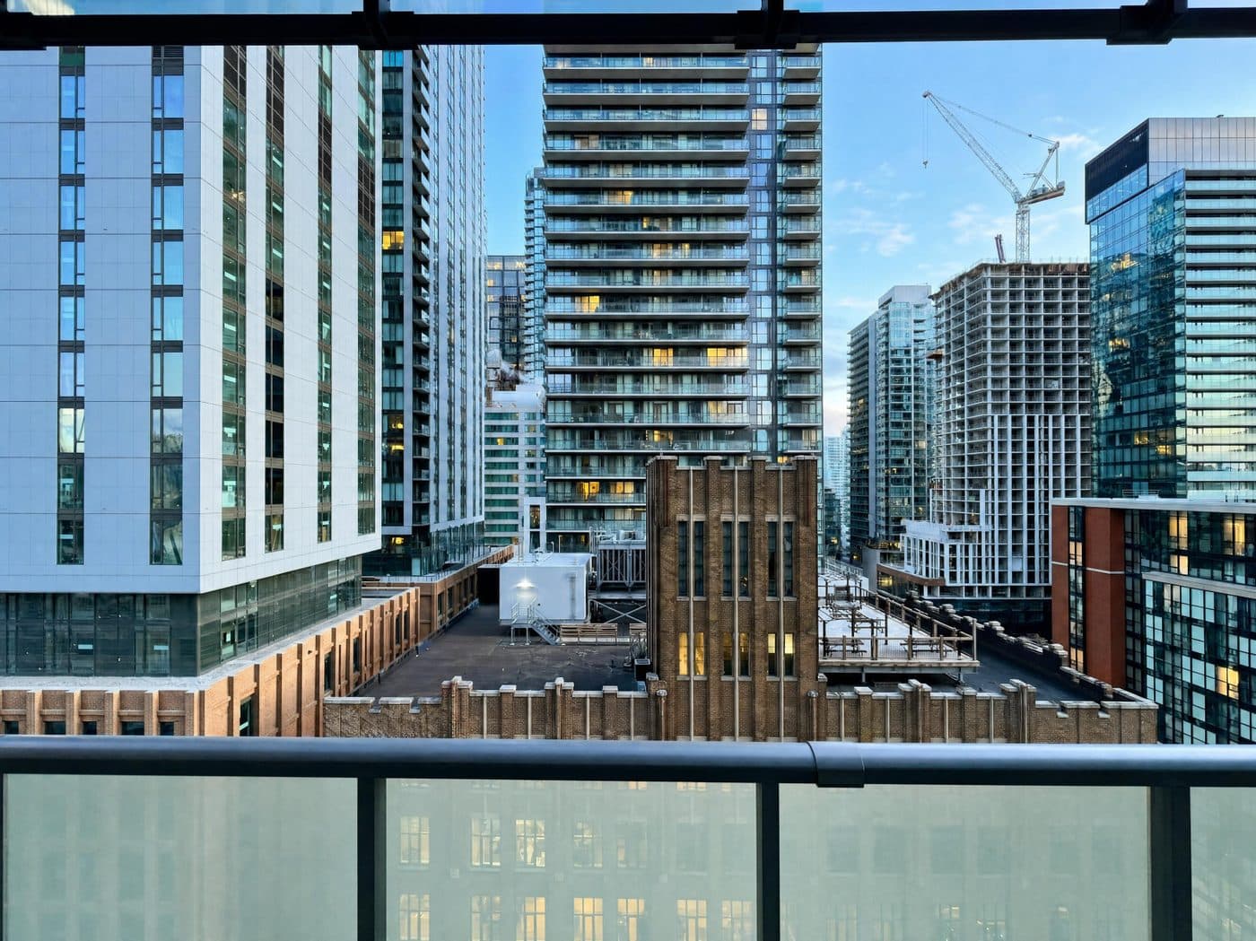 Downtown Toronto condo towers at dusk, seen from the balcony of a RivetStays-managed suite at The Peter, 101 Peter St